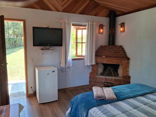 1 dormitorio con chimenea y TV en la pared en Chalé dois irmãos en Visconde De Maua