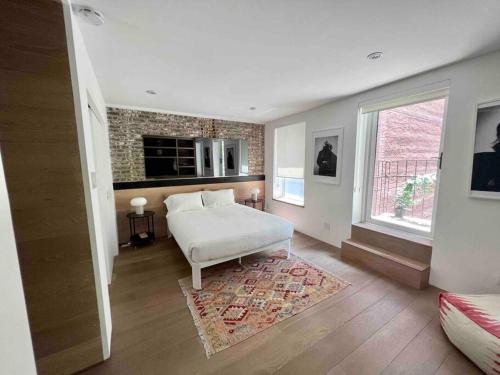 um quarto com uma cama branca e uma parede de tijolos em Superb Duplex Penthouse in FIDI em Nova York