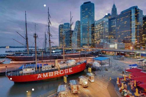 a red boat is docked in a harbor with a city at Superb Duplex Penthouse in FIDI in New York