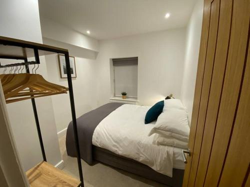 a bedroom with a bed with white sheets and blue pillows at The Print Rooms, Old Printworks, Winchester in Winchester