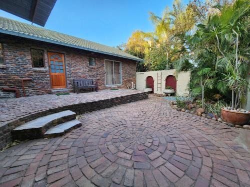 a brick house with a brick patio with a bench at Flamboyant Guesthouse in Bela-Bela