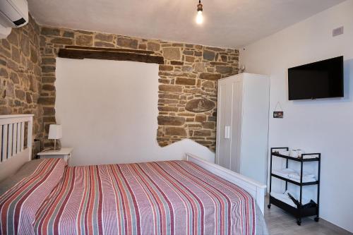 a bedroom with a bed and a stone wall at Eureka Room & Breakfast in Pietrapertosa
