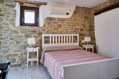 a bedroom with a bed and a stone wall at Eureka Room & Breakfast in Pietrapertosa