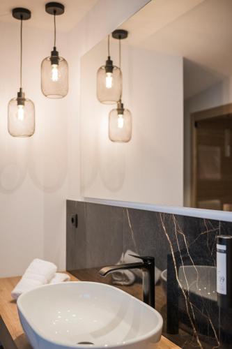 a bathroom with a white sink and three lights at Montanaris Alpine - Active - Relax in Villabassa