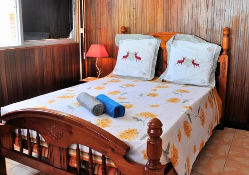 a bedroom with a wooden bed with a white blanket and pillows at Villa Des Sources Chaudes in Bouillante