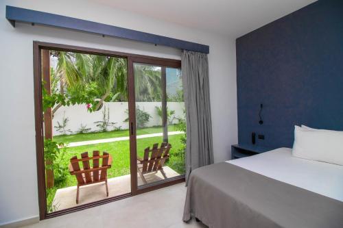 1 dormitorio con 1 cama y puerta corredera de cristal en My Blue Hotel Holbox en Holbox Island