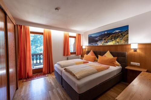 a bedroom with a large bed with orange curtains at Hotel & Chalets Lampllehen in Marktschellenberg