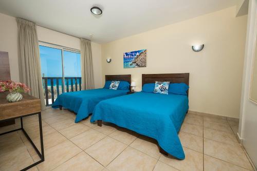 a bedroom with two beds and a balcony at Beachfront Palapa21 - Jan Thiel in Jan Thiel