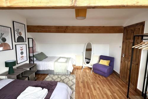 a bedroom with two beds and a purple chair at Leeds Cosy House in Leeds