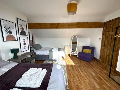 a bedroom with two beds and a blue chair at Leeds Cosy House in Leeds