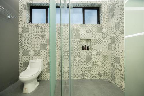a bathroom with a toilet and a glass shower stall at Hotel Patio Santiago in Querétaro