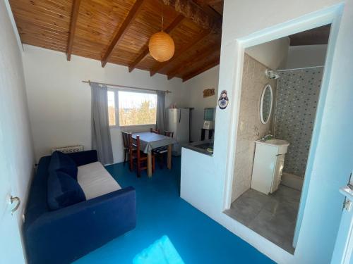 sala de estar con sofá azul y cocina en La Casa del Rey de las Ballenas en Puerto Pirámides