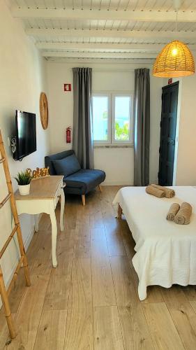 a room with two beds and a table and a couch at Cantinho de Milfontes 1 in Vila Nova de Milfontes