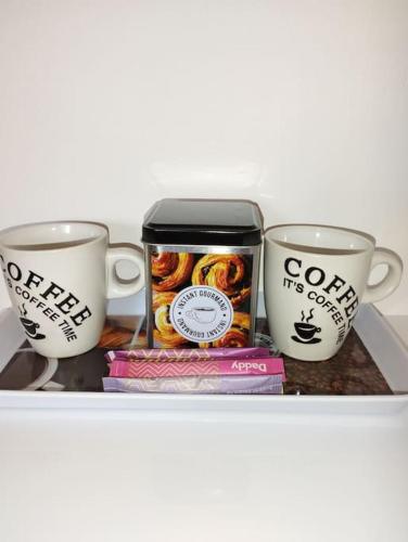 une étagère avec trois tasses à café et des livres dans l'établissement Le ptit nid de Louviers TV/Fibre, à Louviers