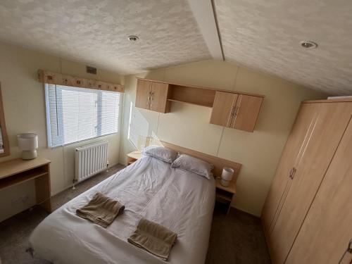 a small bedroom with a bed and a window at Lovely 2-Bed Caravan at St Osyth Caravan Park in Clacton-on-Sea