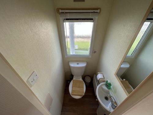 a small bathroom with a toilet and a sink at Lovely 2-Bed Caravan at St Osyth Caravan Park in Clacton-on-Sea