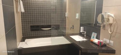 a bathroom with a tub and a sink and a phone at Hotel Cosmopolitan in Ahmedabad