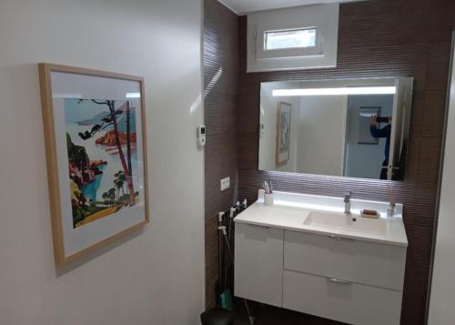 uma casa de banho com um lavatório branco e um espelho. em Superbe appartement piscine, tennis, vue mer et décoré avec goût em Cassis