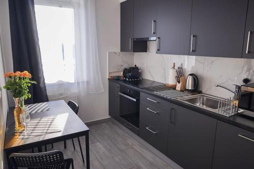 - une cuisine avec des placards noirs, une table et un évier dans l'établissement Apartament Carolina, à Rzeszów