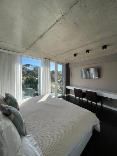 1 dormitorio con cama blanca y ventana grande en INN Carilo en Cariló