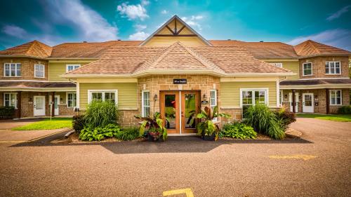 a large yellow house with a red door at Splendid Mountain View Condo with Pool & BBQ- Ski, MTB, Cycling, Golf, Telework! in Bromont