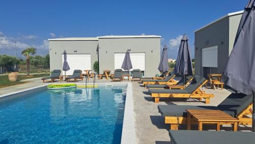 a swimming pool with lounge chairs and umbrellas at Olympia Suites in Pýrgos