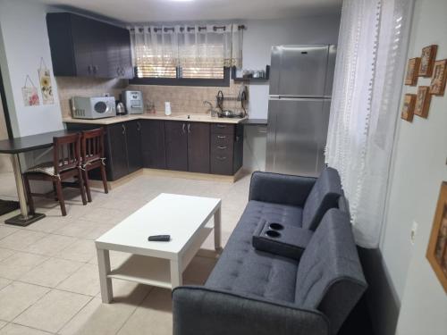 a living room with a couch and a table and a kitchen at B&B Amit 18 minutes from the airport - אירוח כפרי עמית 18 דקות משדה תעופה in Petaẖ Tiqwa