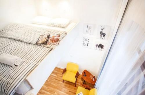a small bedroom with a bed and a yellow chair at Sopot Retro Apartment in Sopot