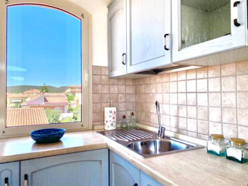 una cucina con lavandino e una grande finestra di Casagliana Apartments a Golfo Aranci