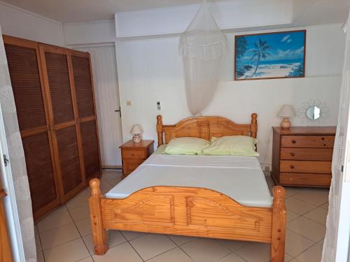 a bedroom with a wooden bed and two dressers at TI-WAIT in Sainte-Anne