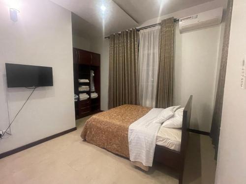 um quarto com uma cama e uma televisão de ecrã plano em Dar Villa em Dar es Salaam