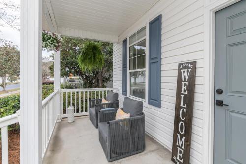 a front porch with two chairs and a sign on it at Encanto of the Lowcountry in Old Town Bluffton in Bluffton