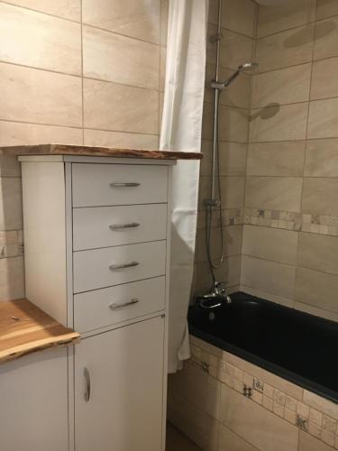 La salle de bains est pourvue d'une armoire blanche et d'une baignoire. dans l'établissement Petite maison avec jardin privé, au Malzieu-Ville