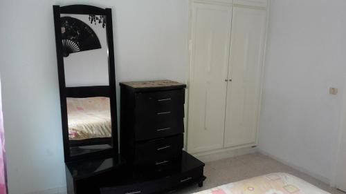 a bedroom with a black dresser and a mirror at Ahlem palmeraies résidence in La Marsa