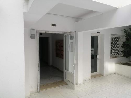 a hallway with an open door in a white room at Ahlem palmeraies résidence in La Marsa