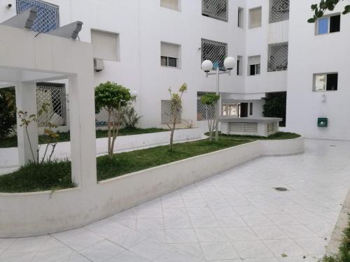 a large white building with a courtyard with trees at Ahlem palmeraies résidence in La Marsa