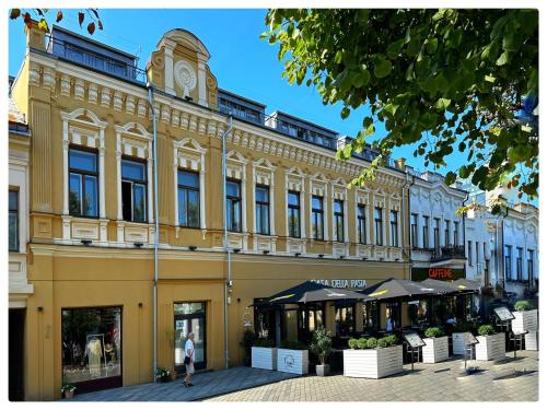 a large yellow building with a clock tower on top at Apartaments in the city centre in Kaunas