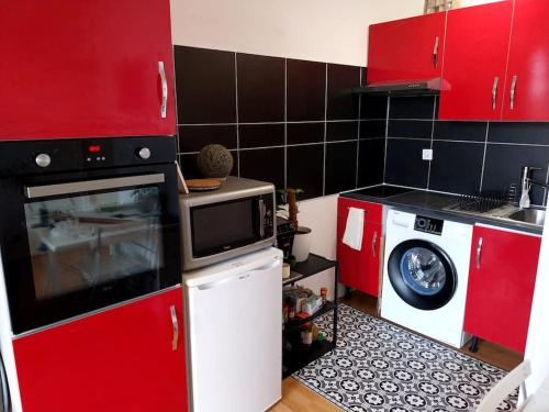 una piccola cucina con armadi rossi e forno a microonde di Charmant Duplex aux Minimes a Tolosa