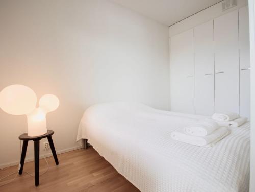 Dormitorio blanco con cama y taburete en Nordic Quality Apartments- Feel the North en Rovaniemi