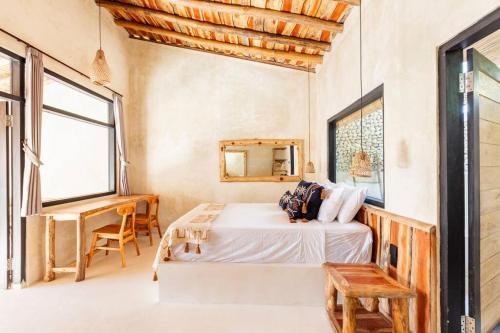Un dormitorio con una cama, un escritorio y ventanas. en Angatu Villas 1 Padang - Padang, en Uluwatu