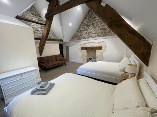 a attic bedroom with two beds and a fireplace at Large Historic Farmhouse in Rhondda Valley Perfect for Groups with Hot Tub in Blaencwm