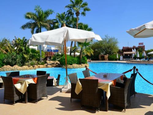 Apartments For Rent in Delta Sharm Resort في شرم الشيخ: طاولة مع مظلة بجانب مسبح