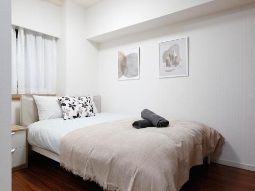 a white bedroom with a bed and a window at Duo Scala Shinjuku 東新宿 in Tokyo