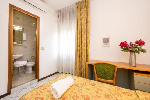 a hotel room with a bed and a desk and a bathroom at Camelia Rooms Venice Guesthouse in Mestre