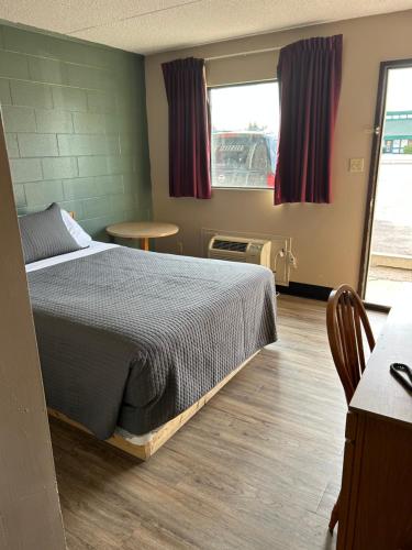 a bedroom with a bed and a table and a window at Cedar Inn in Lloydminster