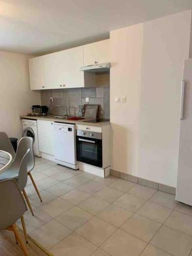 - une cuisine avec des appareils blancs, une table et des chaises dans l'établissement Charmant havre de paix à la campagne, à Jouarre