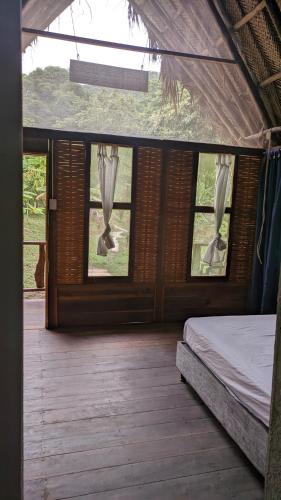 1 dormitorio con ventanas y 1 cama en una casa en Ecohab - Ciudad perdida, en Santa Marta