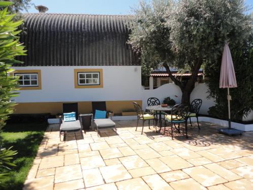 a patio with a table and chairs and an umbrella at Monte dos Aroeirais in Fronteira