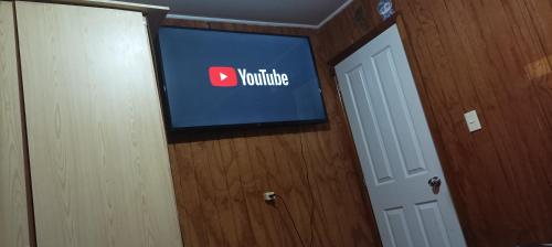 Casa Turística Arauco في أراوكو: تلفزيون في غرفة مع علامة اليوتيوب على الحائط