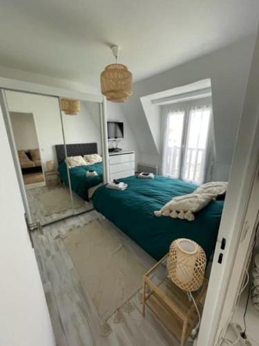 - une chambre avec un lit vert et un miroir dans l'établissement Appartement Vue mer et espaces verts proche Deauville Traveller Awards 2025, à Blonville-sur-Mer